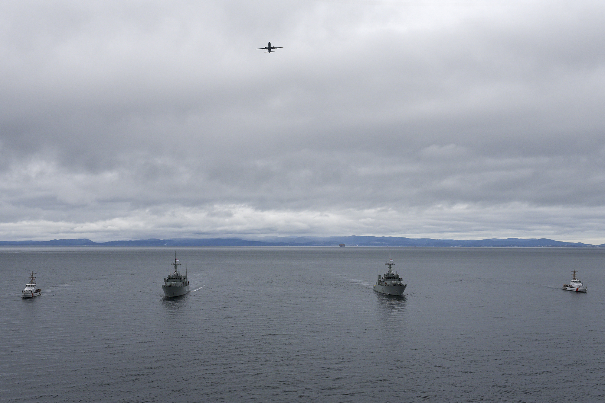 A U.S. Navy P-8 Poseidon Naval Air Station Whidbey Island aircraft flies over U.S. Coast Guard Cutter Blue Shark [WPB 87360] and U.S. Coast Guard Cutter Osprey [WPB 87307] as they transit alongside HMCS Saskatoon and HMCS Yellowknife from the Royal Canadian Navy during a joint exercise in the Salish Sea on Feb. 17, 2022. During a deployment scheduled for later this spring, HMCS Saskatoon and HMCS Yellowknife will work closely with the U.S. Coast Guard and U.S. Navy. Photo: U.S. Coast Guard